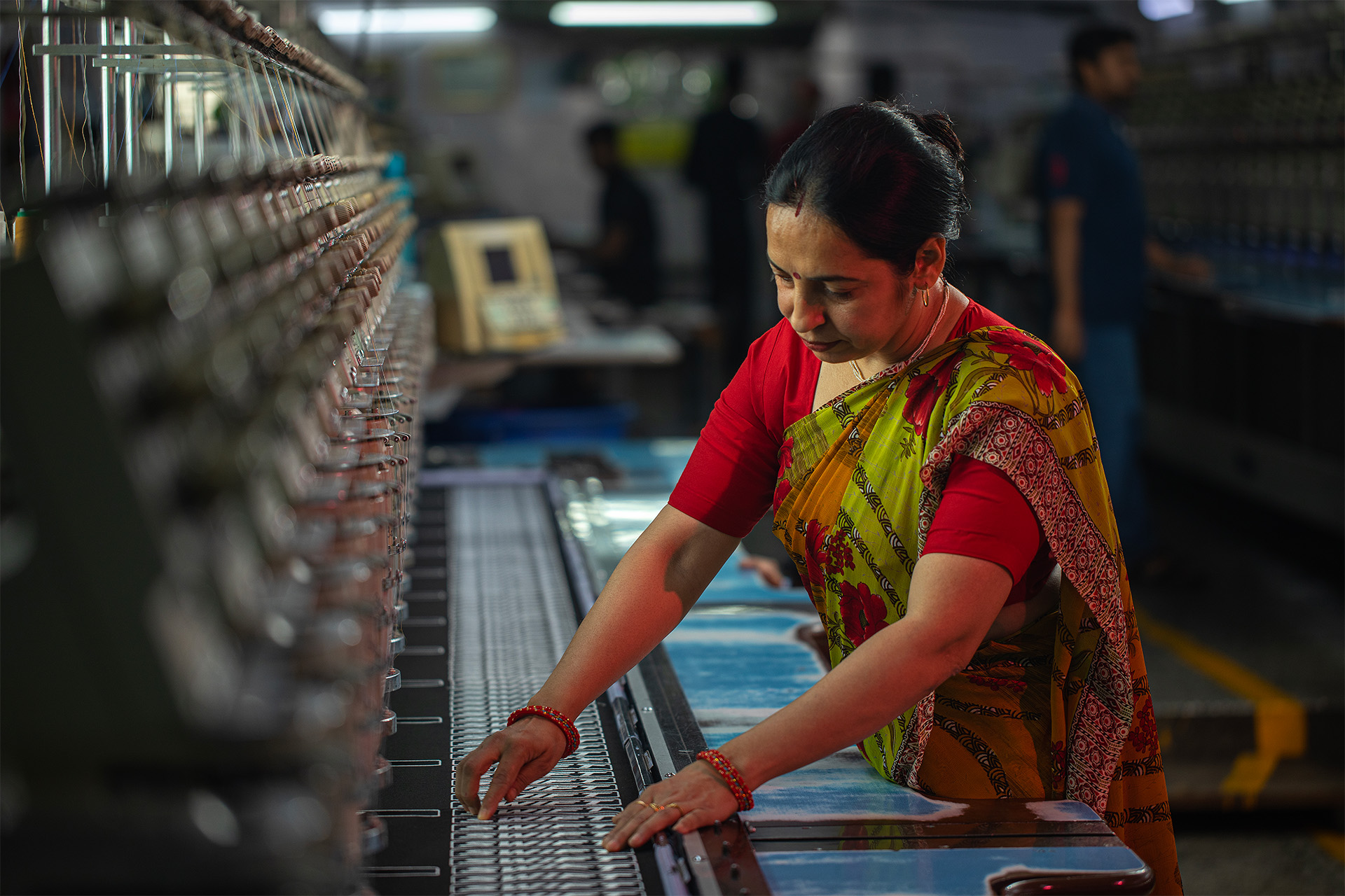 Female worker operating machinery in textile factory