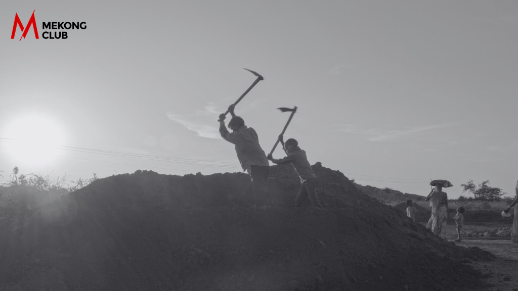 Silhouetted workers laboring at sundown in a rural Indian field